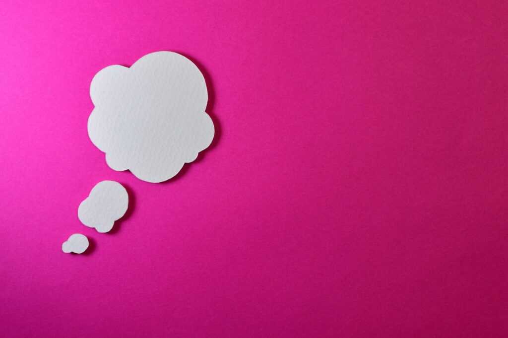 Paper thought bubble over bright pink background, ideal for creative concepts.